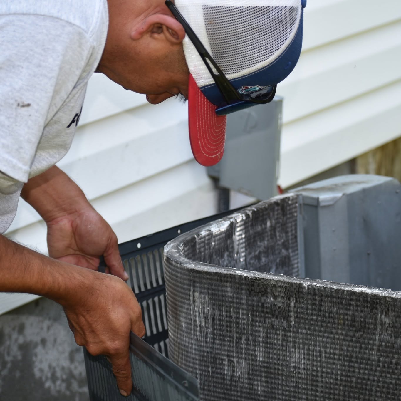 PZ Heating & Cooling technician inspecting an AC condenser coil