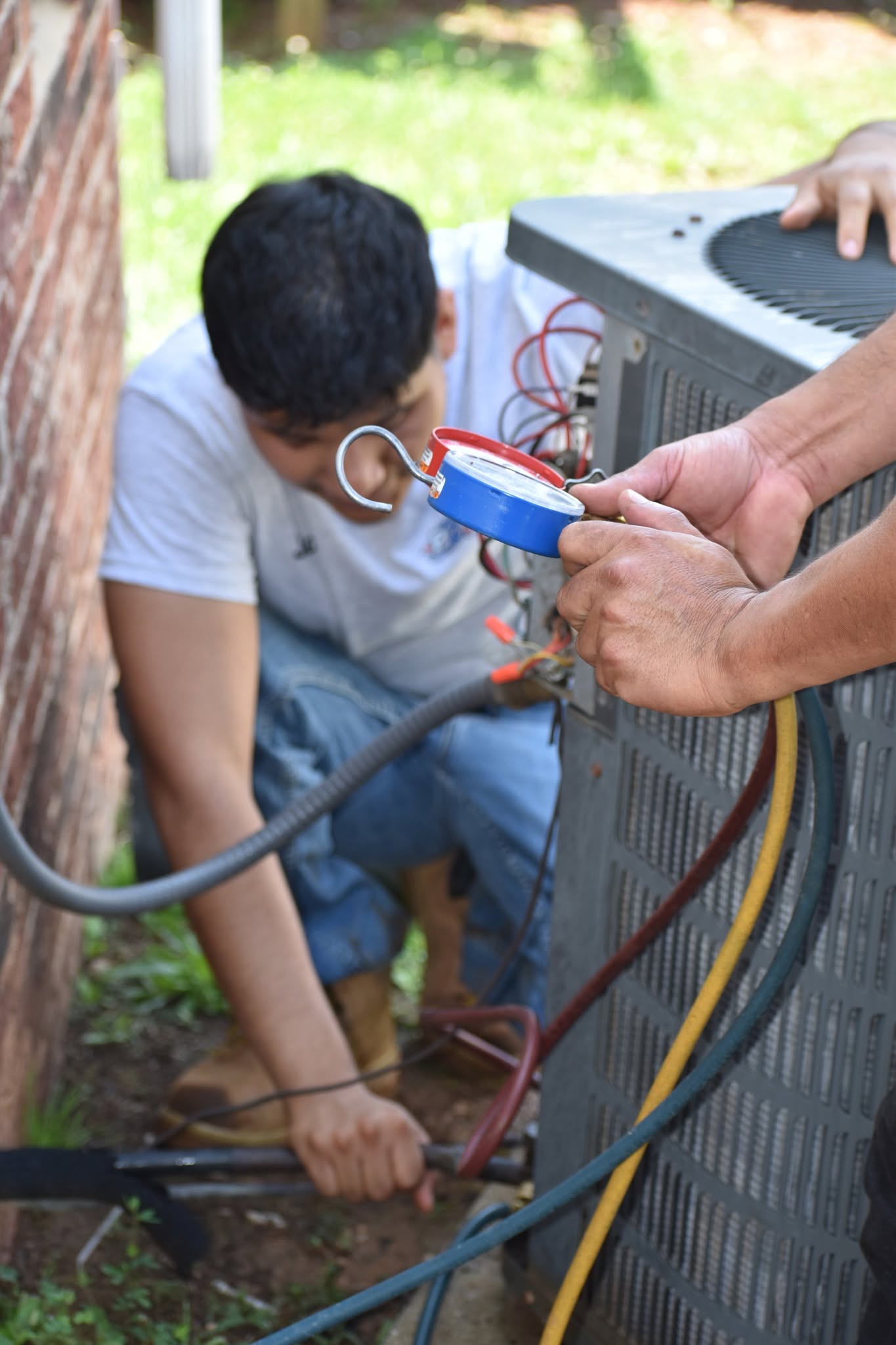 Two technicians repairing a residential AC condenser